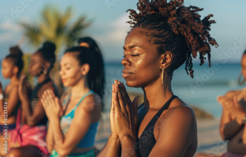 Group of young women doing yoga on the beach at sunrise