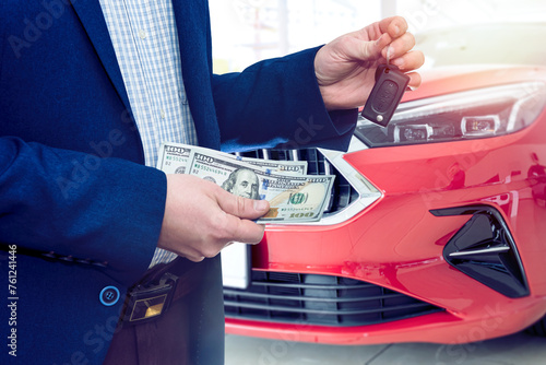 male hand hold dollar money banknotes near car in showroom, loan and buying car concept