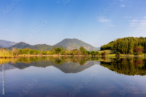Beautiful landscape with reflection of mountain range on water at Tha Khoei reservoir in Ratchaburi, Thailand. 