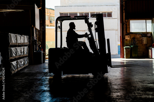 Mature worker driving forklift at factory photo