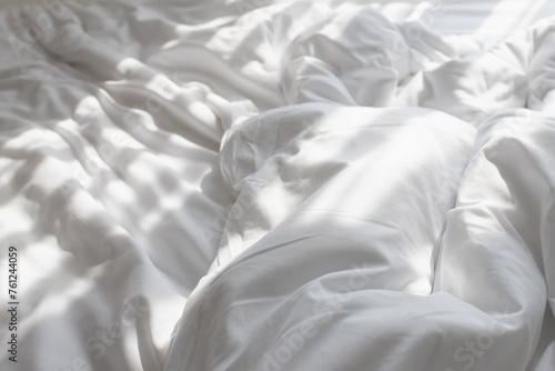 Unmade bed with shades of sunlight through the curtain in morning. photo