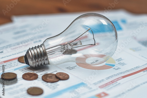 Electricity bills with light bulb and coins photo