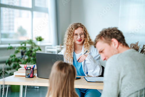 Smiling doctor having discussion with patients in clinic photo