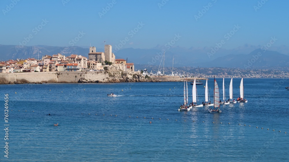 Paysage de côte avec les bateaux d’une école de voile naviguant en mer Méditerranée, dans la baie de la ville d’Antibes, sur la côte d’azur, dans les Alpes-Maritimes (France)