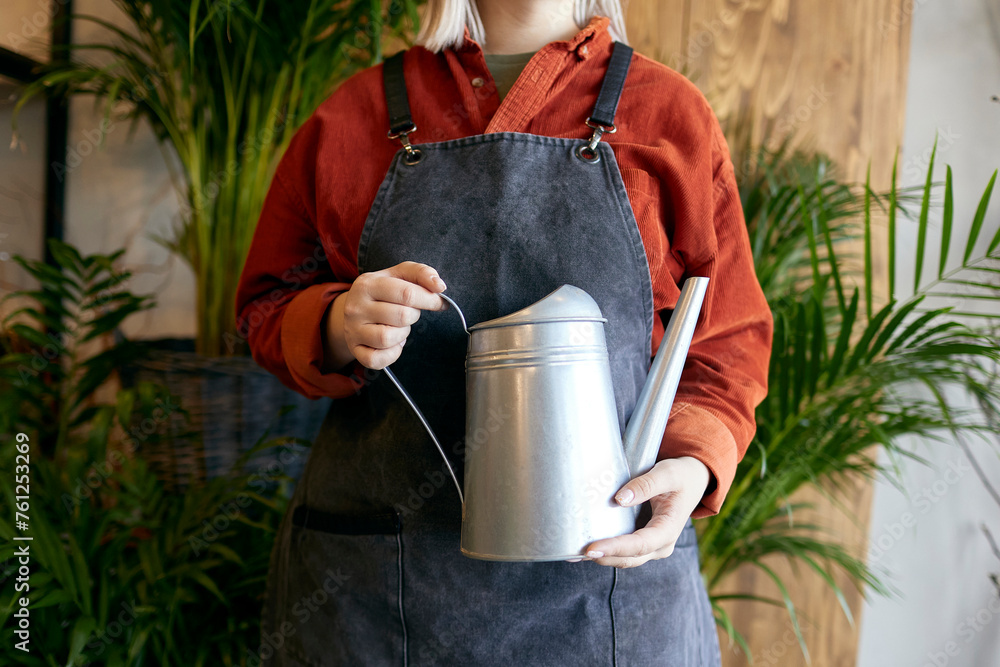 © Westend61 - Gardener standing with watering can near plants