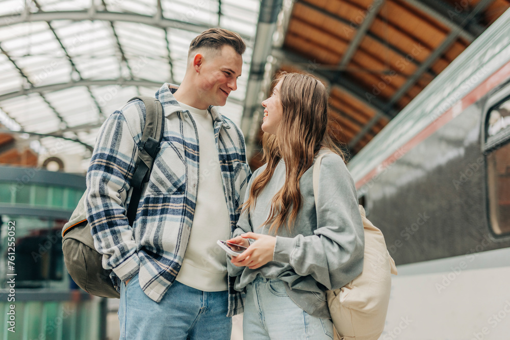 Young couple with backpacks standing at railroad station Young couple with backpacks standing at railroad station