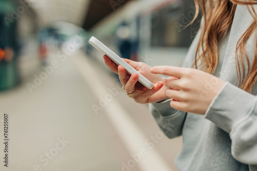 Woman surfing net through smart phone at station photo