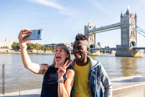Multiracial tourists friends sticking out tongue and talking selfie on vacation photo
