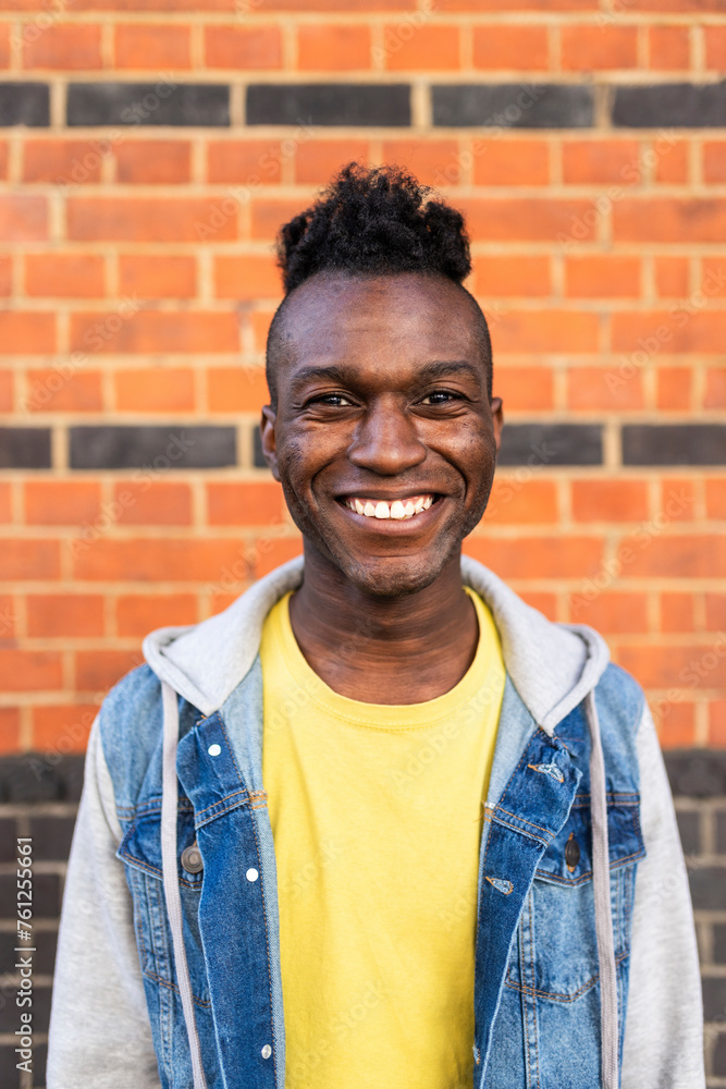 Smiling young man standing in front of brick wall