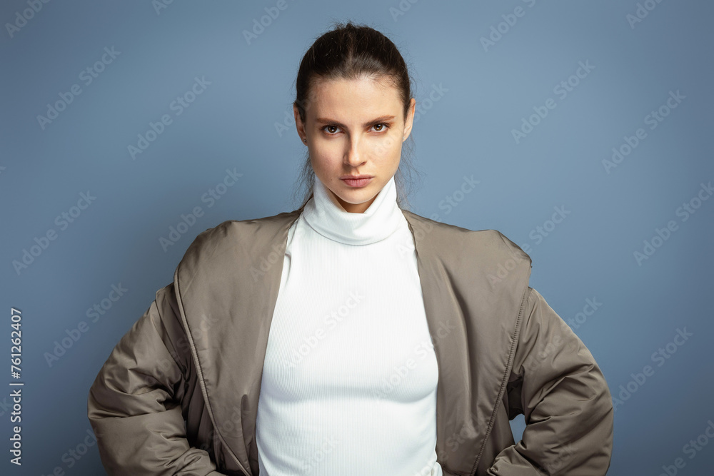 Fototapeta premium Young confident attractive woman wearing a grey coat during autumn and winter, isolated on grey studio background
