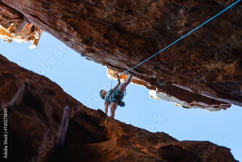 Woman rock climbing on orange rock face