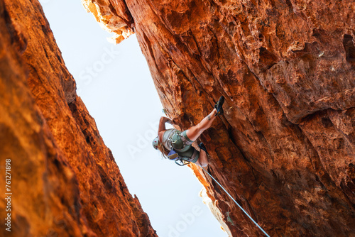 Woman rock climbing on orange rock face