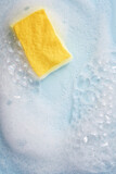Cleaning sponge and a soapy foam on a blue background.