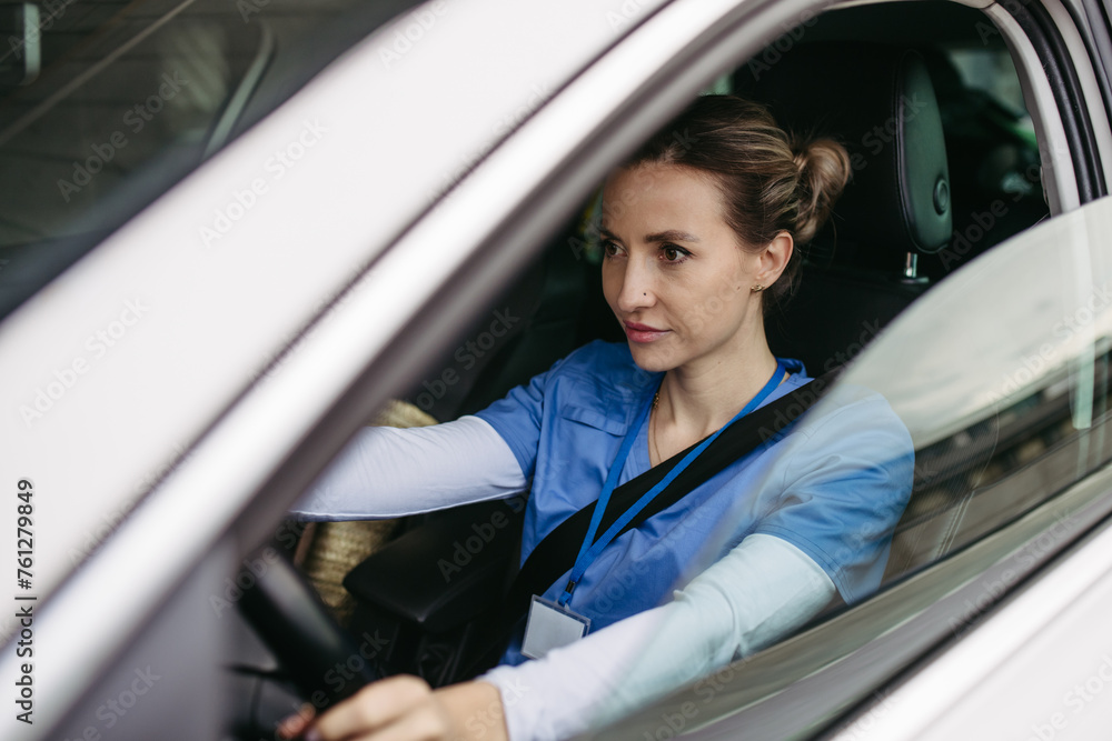 Obraz premium Female nurse sitting in car, going home from work. Female doctor driving car to work, on-call duty. Work-life balance of healthcare worker.