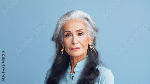 Elegant, smiling, elderly, chic Latino, Spain woman with gray long hair and perfect skin, on a blue background, banner.
