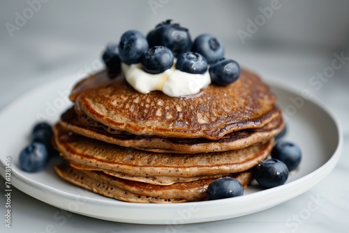 buckwheat pancakes in a stack, topped with blueberries and a dollop of Greek yogurt, viewed from a side angle