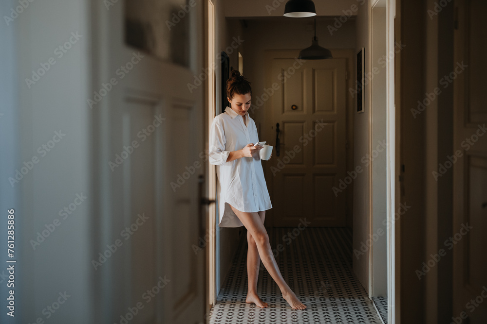 Young woman in the morning, carrying cup of coffee and returning back to bed. Side view of beautiful single woman at home alone over the weekend.