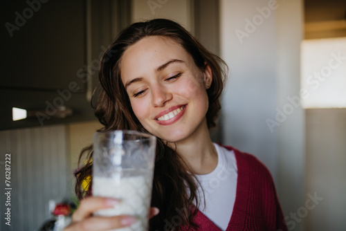 Fotografía Beautiful woman drinking glass of plant-based milk in the kitchen