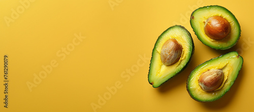 Halved avocados on yellow background with copy space, banner. Top view