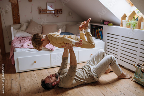 Father an son doing ariplane game, lifting boy up with hands like plane, laughing together. Boys dad. Unconditional paternal love, Father's Day concept. photo