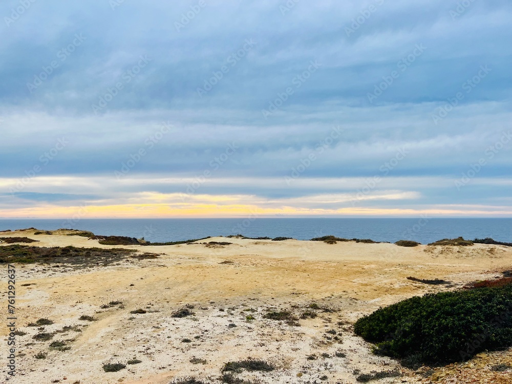 Cloudy sunset at the ocean, rocky ocean coast, sunset ocean horizon, way to the ocean