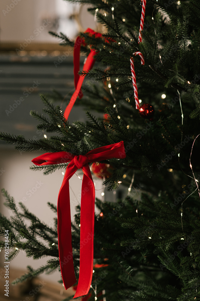 Beautiful New Year decor, the Christmas tree is decorated with red bows in the stylish interior of the living room
