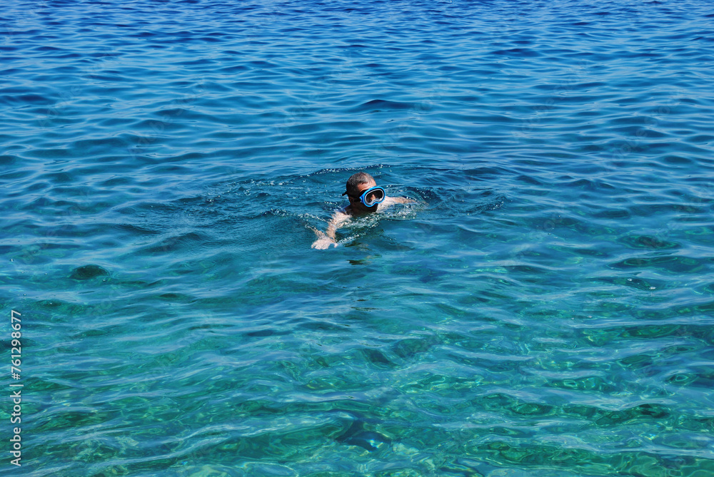 Horizontal picture of man swiming with mask and exploring Adriatic sea bottom. Young man swiming in a diving mask