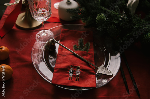 Beautiful New Year decor, a Christmas table with a red tablecloth and candles, festive dishes and glasses