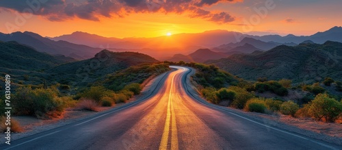 Winding road through desert landscape at sunset