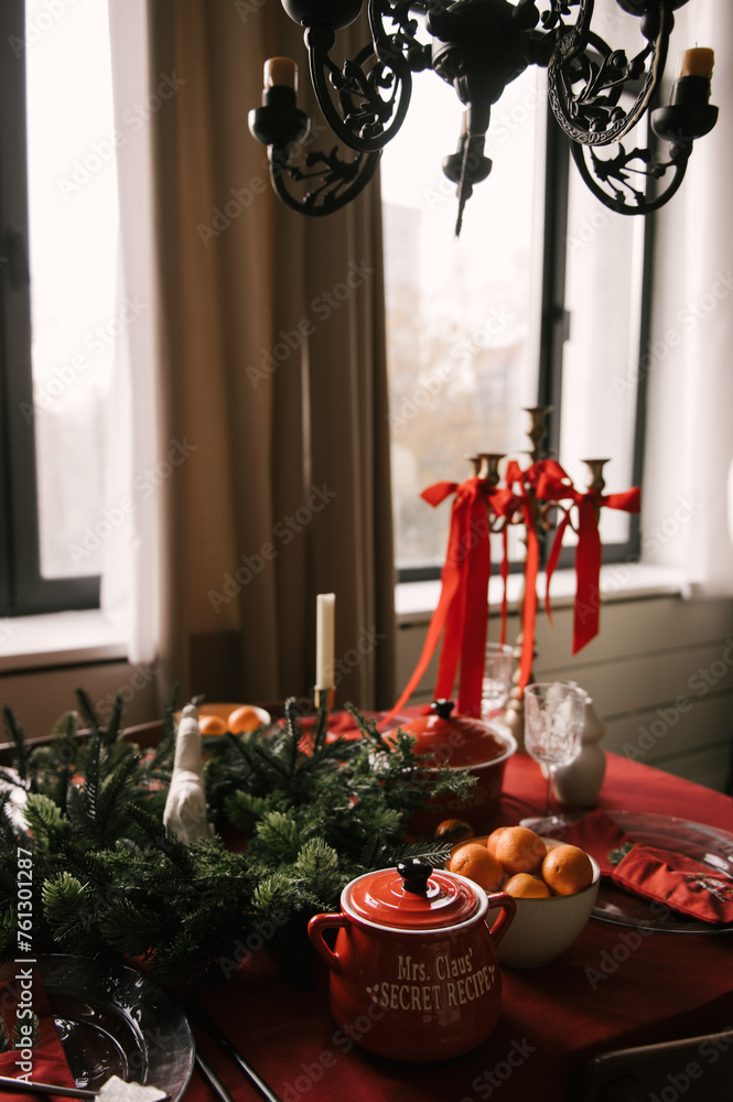 Beautiful New Year decor, a Christmas table with a red tablecloth and candles, festive dishes and glasses