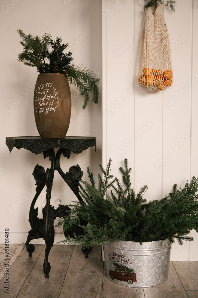 Beautiful New Year decor, a Christmas wreath made of spruce on the wall, a handmade woven string bag with tangerines