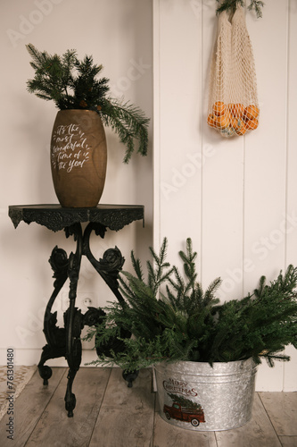 Obraz na płótnie Beautiful New Year decor, a Christmas wreath made of spruce on the wall, a handmade woven string bag with tangerines w salonie