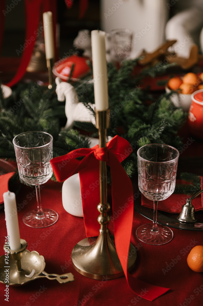 Beautiful New Year decor, a Christmas table with a red tablecloth and candles, festive dishes and glasses