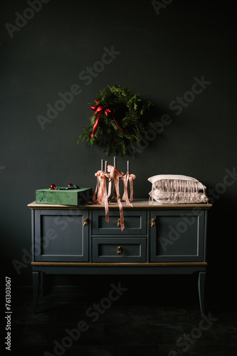 Beautiful New Year decor, a Christmas wreath on a vintage chest of drawers in a stylish dark living room interior