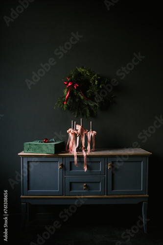 Obraz na płótnie Beautiful New Year decor, a Christmas wreath on a vintage chest of drawers in a stylish dark living room interior w salonie