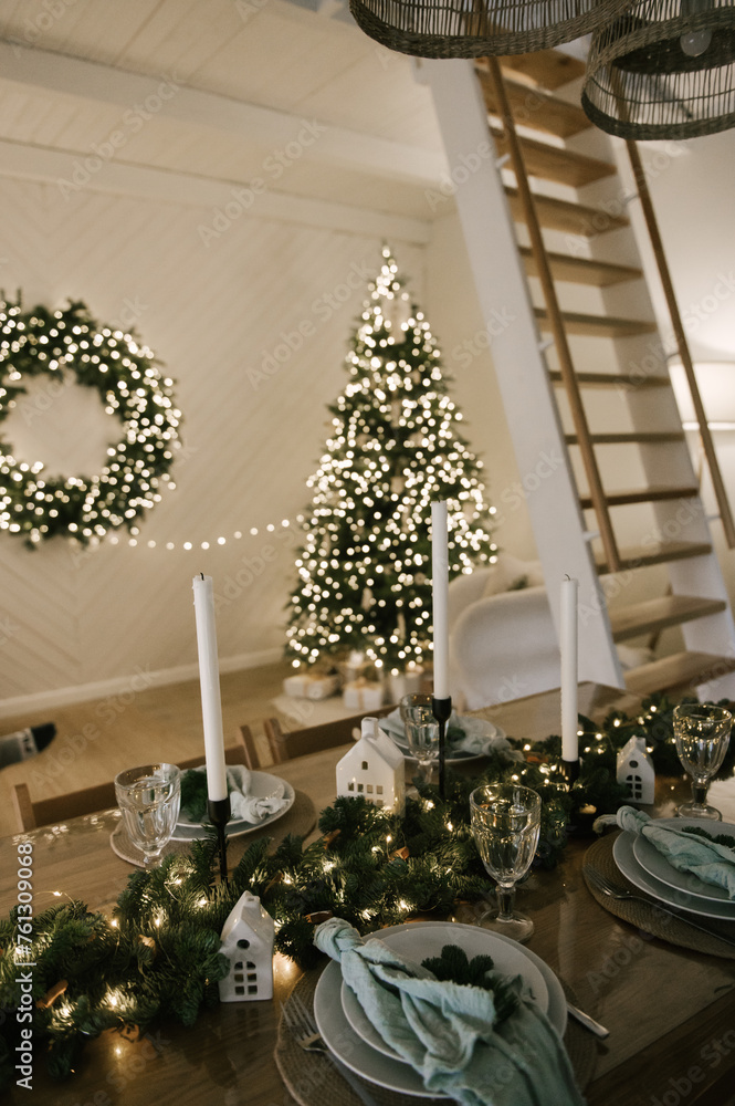 Beautiful New Year's decor at home, the table is set for the holiday against the background of the lights of the Christmas tree