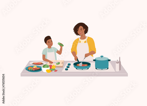 Black Mother And Son Preparing Food Together In The Kitchen. Smiling Black Little Son In Apron Cutting Cucumber With Knife. Mother Cooking Steak With Frying Pan. Half Length.