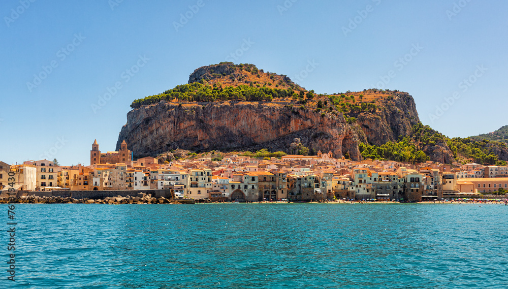 Panoramic view of Cefalù, Metropolitan City of Palermo, coastal town in Sicily, Italy.  Old buidings, the Duomo, a Norman Cathedral and La Rocca, a rocky mountain, summer time, august 2023.