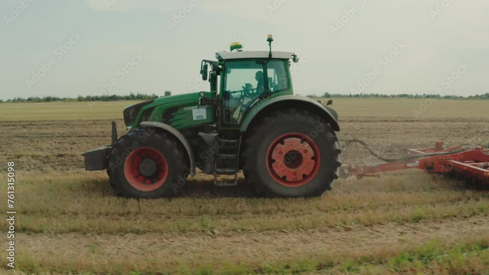 A tractor in an agricultural field while working with a plow. Smooth shots of a tractor from a drone at low altitude. A tractor in an agricultural field while working with a plow. Smooth shots of a tractor from a drone at low altitude.