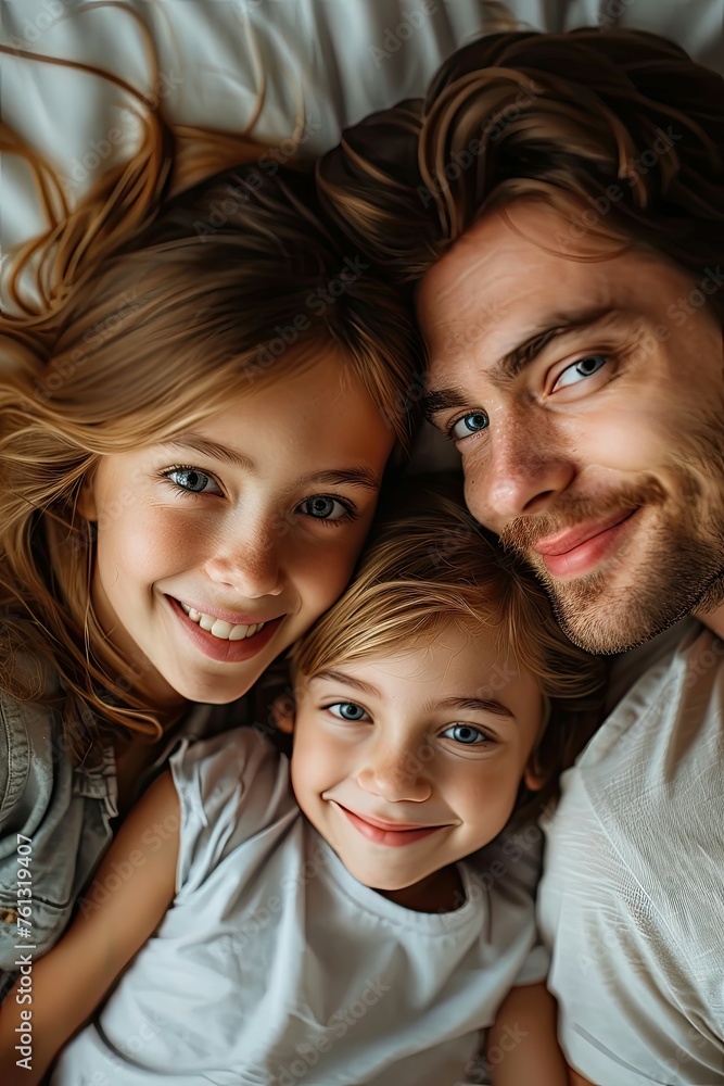 Father with daughters lying on bed, sharing a loving moment.