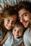 Father with daughters lying on bed, sharing a loving moment.