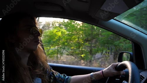 Wallpaper Mural Profile of hippie man in sunglasses driving a motor car with sunlight at background. Young male hipster with long hair riding on auto to rural road. Concept of journey and trip. Close up Slow motion Torontodigital.ca