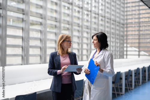 Doctor talking to pharmaceutical sales representative, presenting new pharmaceutical product. Hospital manager talking with doctors team. photo