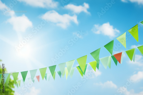 Blue sky with few clouds and bunch of green flags hanging from sky