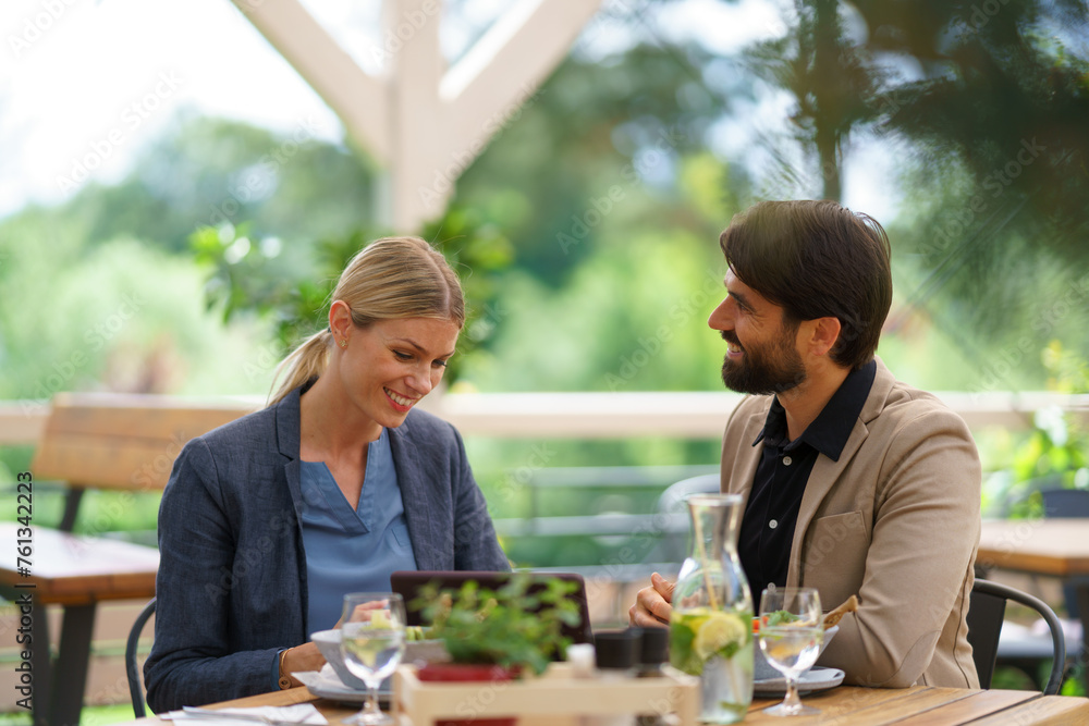 Business lunch for two managers, discussing new business project. Couple sitting outdoors on terrace restaurant, having dinner date. Business lunch for two managers, discussing new business project. Couple sitting outdoors on terrace restaurant, having dinner date.