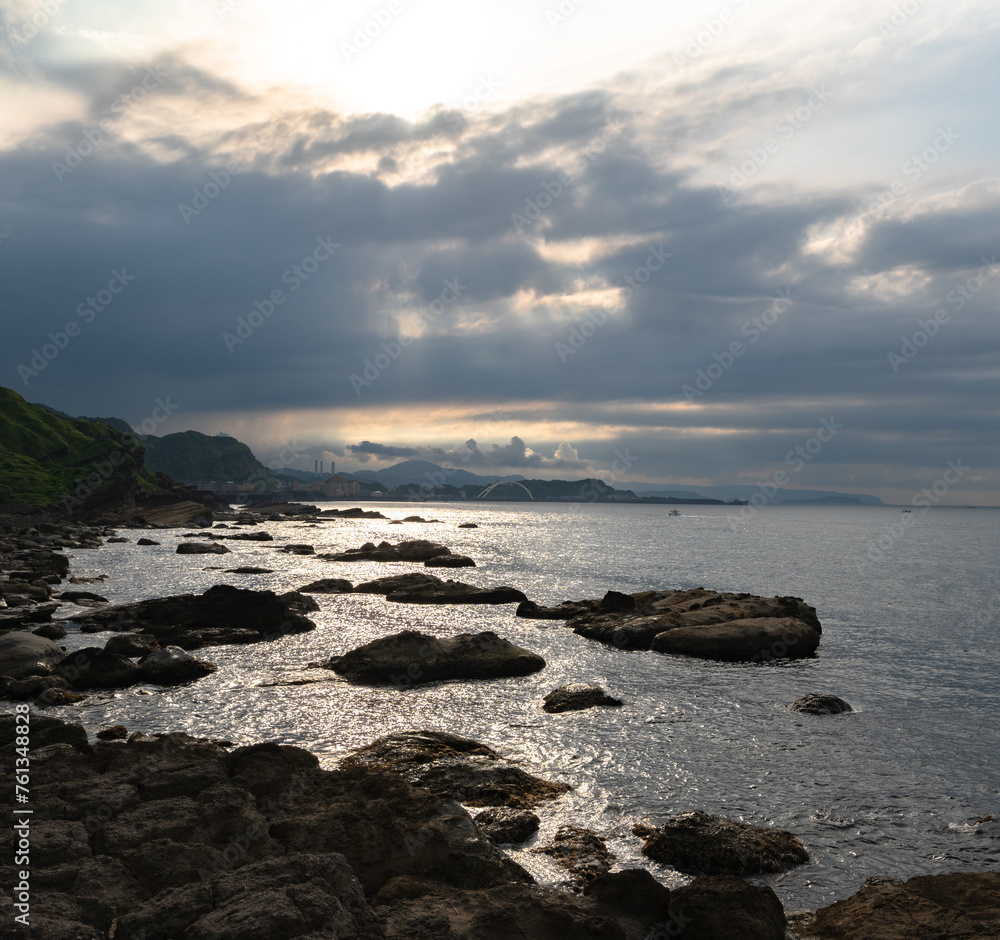 Cloudy day in the coastline, ocean looks peaceful and reflect sunlight which go through the cloud, in Keelung, Taiwan.