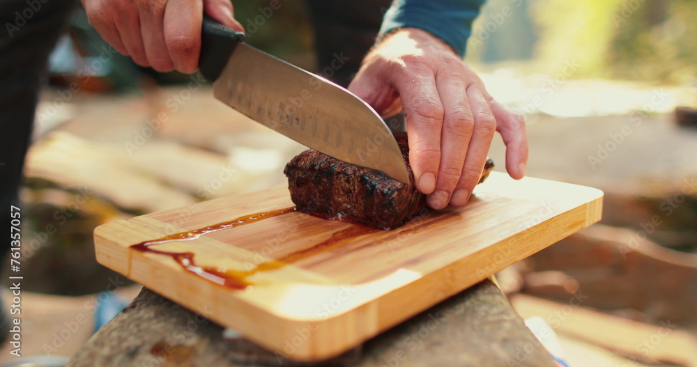 A man is slicing a juicy, freshly cooked steak outdoors. A man is slicing a juicy, freshly cooked steak outdoors.