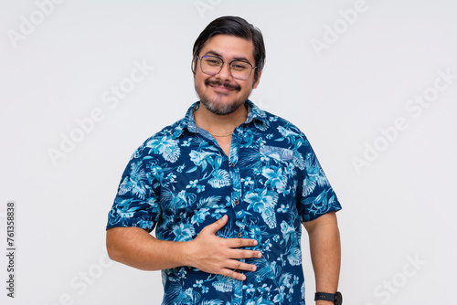 Content middle aged man in a floral Hawaiian shirt, rubbing his belly indicating fullness and satisfaction, isolated on white. photo