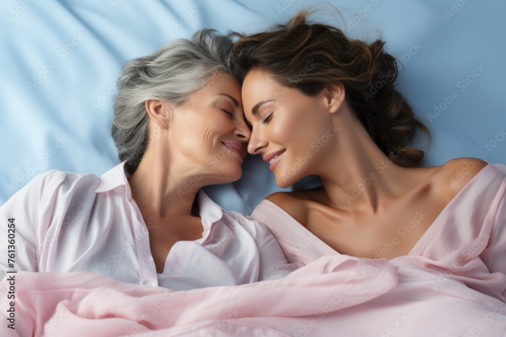 Two women are laying on bed, one of them is older and other is younger ...