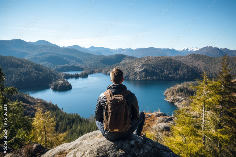 Man sits on rock overlooking lake
